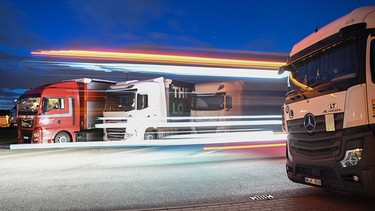 Lastwagen stehen in der Nacht auf einer Raststätte auf der Autobahn. | Bild: picture alliance/dpa | Bernd Weißbrod
