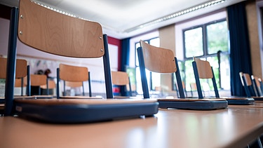 Stühle stehen auf Tischen in einem Klassenraum.  | Bild: picture alliance/dpa | Fabian Strauch