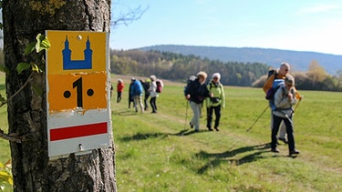 Eine Wandergruppe passiert einen Wegweiser auf der Gottesgartenrunde | Bild: Tourismusregion Obermain-Jura / A. Lochner