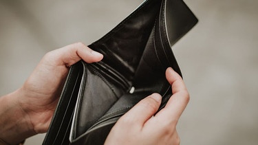 Hände öffnen ein leeres Portemonnaie. | Bild: stock.adobe.com/interstid
