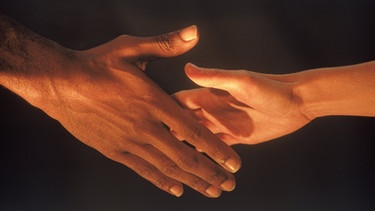 Ein Farbiger und ein Weißer reichen einander die Hände | Bild: picture-alliance/dpa