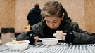 Ein hungriger Junge erhält im Znamianka eine warme Mahlzeit. | Bild: Straßenkinder e.V.