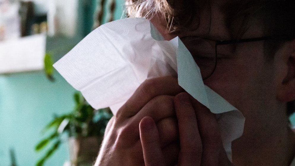 Ein Mann mit Taschentuch schnäuzt sich die Nase.  | Bild: picture alliance/dpa | Philip Dulian