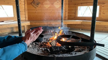 Beerensammeln in Lappland: In einer Kota können wir die Hände über dem Feuer wärmen. Fürs Feuerholz sorgt der finnische Staat - kostenlos für alle Wanderer. | Bild: BR/Petra Martin