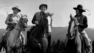 Lomax (Kirk Douglas, Mitte) und Jackson (John Wayne, links) planen, die gepanzerte Kutsche, mit der Pierce das Gold abtransportieren will, zu überfallen. Zusammen mit dem Indianer Levi Walking Bear (Howard Keel, rechts) führen sie den Überfall durch. | Bild: BR/Universal Pictures