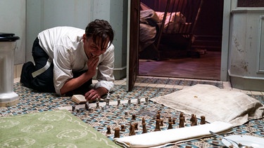 Im Schachfieber: Der Häftling Bartok (Oliver Masucci) spielt gegen sich selbst. | Bild: dpa-Bildfunk/Julia Terjung
