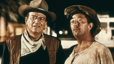 Der gealterte Scharfschütze Cole Thornton (John Wayne, links) kommt nach El Dorado. Von seinem alten Freund Sheriff J. B. Harrah (Robert Mitchum) aber vernimmt er, dass er in eine üble Sache verwickelt werden soll. | Bild: BR/Degeto/Paramount Pictures/SWR/TM