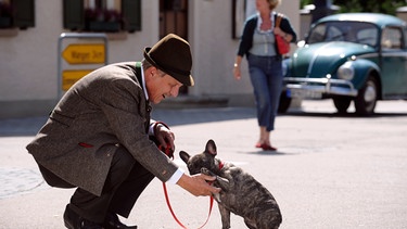 Bürgermeister Schattenhofer (Werner Rom) schließt mit einem streunenden Hund Freundschaft. | Bild: BR/Marco Orlando Pichler