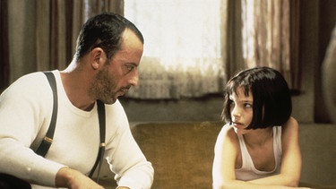 Léon (Jean Reno) betrachtet Mathilda (Natalie Portman) als eine Schülerin, der er den Umgang mit Waffen, nicht aber das Töten beibringt. | Bild: Studiocanal/Thierry Arbogast