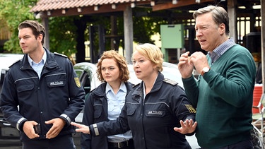 Jakob Frings (Max König, links), Julia Demmler (Wendy Güntensperger, 2. von links), Nele Fehrenbach (Floriane Daniel, 2. von rechts) und Bernhard Pfeil (Martin Armknecht, rechts) beobachten, wie die Tür der Mietwerkstatt aufgeschossen wird. | Bild: ARD/Laurent Trümper