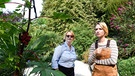 Denise Munk (Zoë Valks, rechts) erklärt Nele Fehrenbach (Floriane Daniel, links), wie man aus dem Wunderbaum Gift extrahieren kann. | Bild: ARD/Laurent Trümper