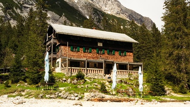 Die Reintalangerhütte im Wettersteingebirge von außen mit Biergarten im Sommer. | Bild: BR/Watch Lola GmbH/Matthias Schwinn