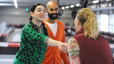 Als Tina (Anita Eichhorn, links) und Naveen (Markus Subramaniam) ein Ehepaar mit Jahrestag spielen müssen, verstärken sich seine Gefühle zu ihr noch weiter. Mit Kartbahnbesitzerin (Mirjam Kendler, rechts). | Bild: BR/Marco Orlando Pichler