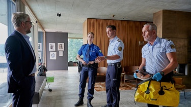 Paul Schott (Tim Wilde, rechts), Jakob Frings (Max König, 2. von rechts) und deren Schweizer Kollegin Ladina Brugger (Chantal Dubs, 3. von rechts) konfrontieren Urs Thaler (Sebastian Krähenbühl, links), den Geschäftspartner des Toten, mit den neuesten Ermittlungsergebnissen. | Bild: ARD/Nicolas Gradicsky