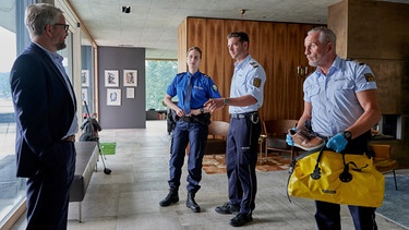 Paul Schott (Tim Wilde, rechts), Jakob Frings (Max König, 2. von rechts) und deren Schweizer Kollegin Ladina Brugger (Chantal Dubs, 3. von rechts) konfrontieren Urs Thaler (Sebastian Krähenbühl, links), den Geschäftspartner des Toten, mit den neuesten Ermittlungsergebnissen. | Bild: ARD/Nicolas Gradicsky