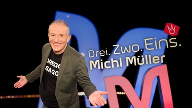 Key Visual Sendereihenbild mit Typo zu "Drei. Zwo. Eins. Michl Müller". Pointiert und süffisant kommentiert der selbsternannte "Dreggsagg" in seiner satirischen Chart-Show "Drei. Zwo. Eins. Michl Müller" die aktuelle Nachrichtenwelt aus Politik, Boulevard und Gesellschaft. | Bild: BR/Andreas Pirchmoser/Montage: BR