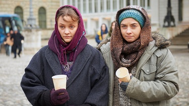 Die Schwestern Tida (Mathilde Bundschuh) und Anuscha Dablika (Cosmina Stratan, rechts) steigen in der Innenstadt mit den anderen Bettlern aus einem Bus. | Bild: ARD Degeto/Bavaria Fernsehproduktion GmbH/BR/Walter Wehner