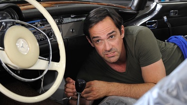 Mike (Harry Blank) begutachtet den Schaden am Oldtimer. | Bild: BR/Marco Orlando Pichler