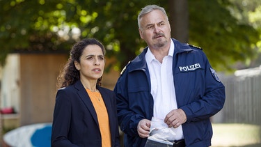 Jasmin Sayed (Sesede Terziyan, links) und Axel Sommer (Oliver Breite, rechts) beobachten die Familie des Opfers. | Bild: ARD/Daniela Incoronato