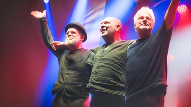 Werner Schmidbauer (rechts) und Martin Kälberer (links) freuen sich bei ihrem Auftritt auf dem Münchner Tollwood-Festival über den Besuch des niederbayerischen Musikers, Kabarettisten und Moderators Hannes Ringlstetter. | Bild: Praetorius GmbH/Michael Praetorius