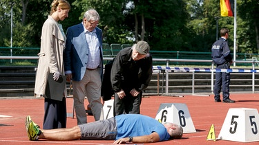 Von links: Dr. Rosalind Schmidt (Helene Grass), Edwin Bremer (Tilo Prückner) und Günter Hoffmann (Wolfgang Winkler) beugen sich über das Mordopfer Ralph Wernheim (Andreas Thürnagel). | Bild: ARD/Kai Schulz