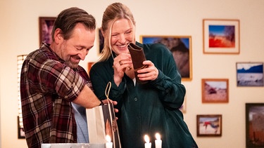 Gregor (Holger Matthias Wilhelm) und Vera (Sybille Waury) freuen sich über ihre Valentinsgeschenke. | Bild: BR/Lena Semmelroggen