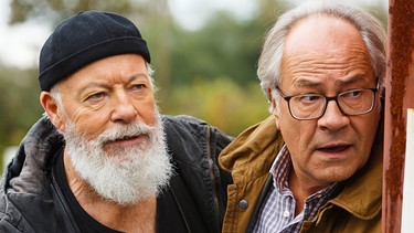 Reinhard Bielefelder (Bill Mockridge, links) und Klaus Schmitz (Hartmut Volle, rechts) beobachten aus einem Versteck heraus Naumann, der offensichtlich in Schwierigkeiten steckt. | Bild: ARD/Kai Schulz