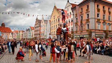 Gaukler unterhalten vor Beginn des Hochzeitszuges die Besucher in der Altstadt mit ihren künstlerischen Darbietungen. Weitere Bilder finden Sie unter www.br-foto.de. | Bild: © BR/Archiv "Die Förderer" e.V./O., honorarfrei - Verwendung gemäß der AGB im engen inhaltlichen, redaktionellen Zusammenhang mit genannter BR-Sendung bei Nennung "Bild: BR/Archiv "Die Förderer" e.V./O."