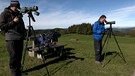 Zwei Vogelzugbeobachter stehen mit Kameras auf einer Bergwiese | Bild: BR