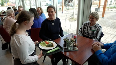 Frau serviert Essen in einem Cafe | Bild: BR