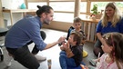 Andreas Weins zeigt Kindergartenkindern das richtige Eincremen | Bild: BR