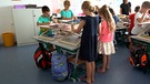 Grundschulkinder stehen während des Unterrichts an ihren Tischen | Bild: BR