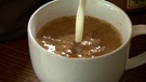 Milch wird in eine Tasse Kaffee gegossen | Bild: BR