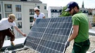 Drei Personen beim Aufbau einer Solaranlage | Bild: BR