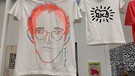 Zwei T-Shirts mit Bild von Warhol und einem Strichmännchen von Haring hängen von der Decke | Bild: BR