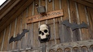 Totenkopf und Schild mit Aufschrift "Joe's Geister-Stadel" hängen an einem Holzgebäude | Bild: BR