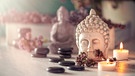 Steine für Hot Stone Massage, brennende Kerzen und ein Buddha. | Bild: stock.adobe.com/Sonja Birkelbach