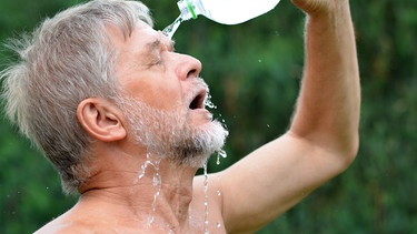 Ein Mann kippt sich eine Flasche Wasser über den Kopf. | Bild: stock.adobe.com/Thomas Mucha