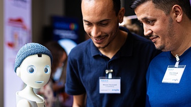 10.09.2024, Niedersachsen, Hannover: Der «soziale" Pflege-Roboter Navel interagiert beim «Innovationsforum Pflege» mit zwei Besuchern. Foto: Moritz Frankenberg/dpa +++ dpa-Bildfunk +++ | Bild: dpa-Bildfunk/Moritz Frankenberg