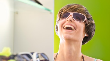 Junge Frau probiert in Boutique Sonnenbrille, lacht. Foto: Johannes Bräutigam, (c)MEV Verlag GmbH/ CD: MEV_AID_BOX_Vol_24 | Bild: MEV/Johannes Bräutigam