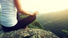 Eine junge Frau meditiert auf einem Berg. | Bild: stock.adobe.com/lzf 
