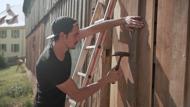 Marco Härtl arbeitet an der Fassade seines neuen Zuhauses. | Bild: BR/Tangram Film Internatinal