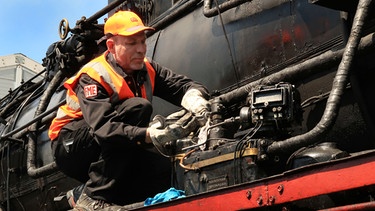 Sebastian Pfaller, Mitglied im Verein Fränkische Museumseisenbahn bei Reparaturarbeiten an einer Dampflok | Bild: Martin Busbach