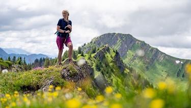 Alix von Melle steht auf dem mit Blumen bewachsenen Bärenköpfle | Bild: BR/Thomas März