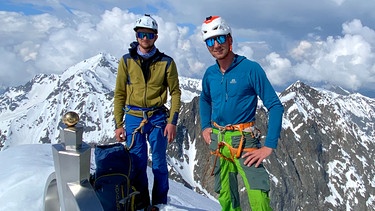 Peter Ortner (r.) und Lukas Sieber stehen am eingeschneiten Gipfelkreuz des Glödis in Osttirol | Bild: BR