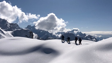 Gruppe von Tourengehern in tief verschneiter Berglandschaft | Bild: BR/Kathrin Denk 