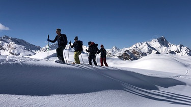 Gruppe von Tourengehern in tief verschneiter Berglandschaft | Bild: BR/Kathrin Denk 