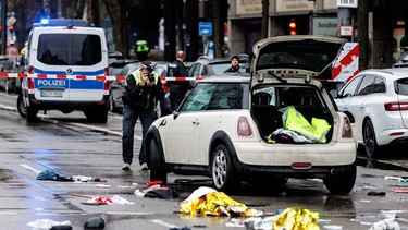 Ein Polizist fotografiert ein Auto am Einsatzort. In der Münchner Innenstadt ist ein Fahrzeug in eine Menschengruppe gefahren. | Bild: picture alliance/dpa | Matthias Balk