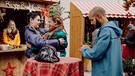 Dahoam is Dahoam: Auf dem Weihnachtsmarkt können sich Tina (Anita Eichhorn, links) und Sarah (Sophie Reiml, Mitte) wieder versöhnen. Mit Naveen (Markus Subramaniam, rechts) und Komparserie. | Bild: BR/Nadya Jakobs