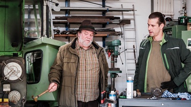 Dahoam is Dahoam: Julian (Sandro Kirtzel, rechts) muss Stadlbauer (Andreas Geiss, links) erklären, wieso der Traktor nicht funkioniert. | Bild: BR/Lena Semmelroggen